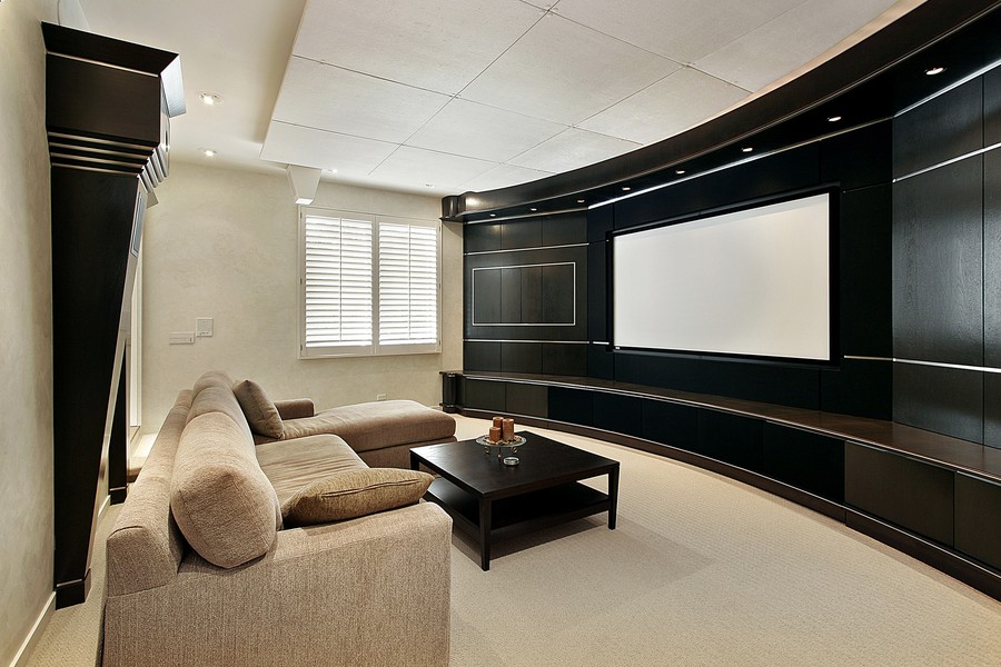 A custom home theater with a large projector screen and sectional seating. 